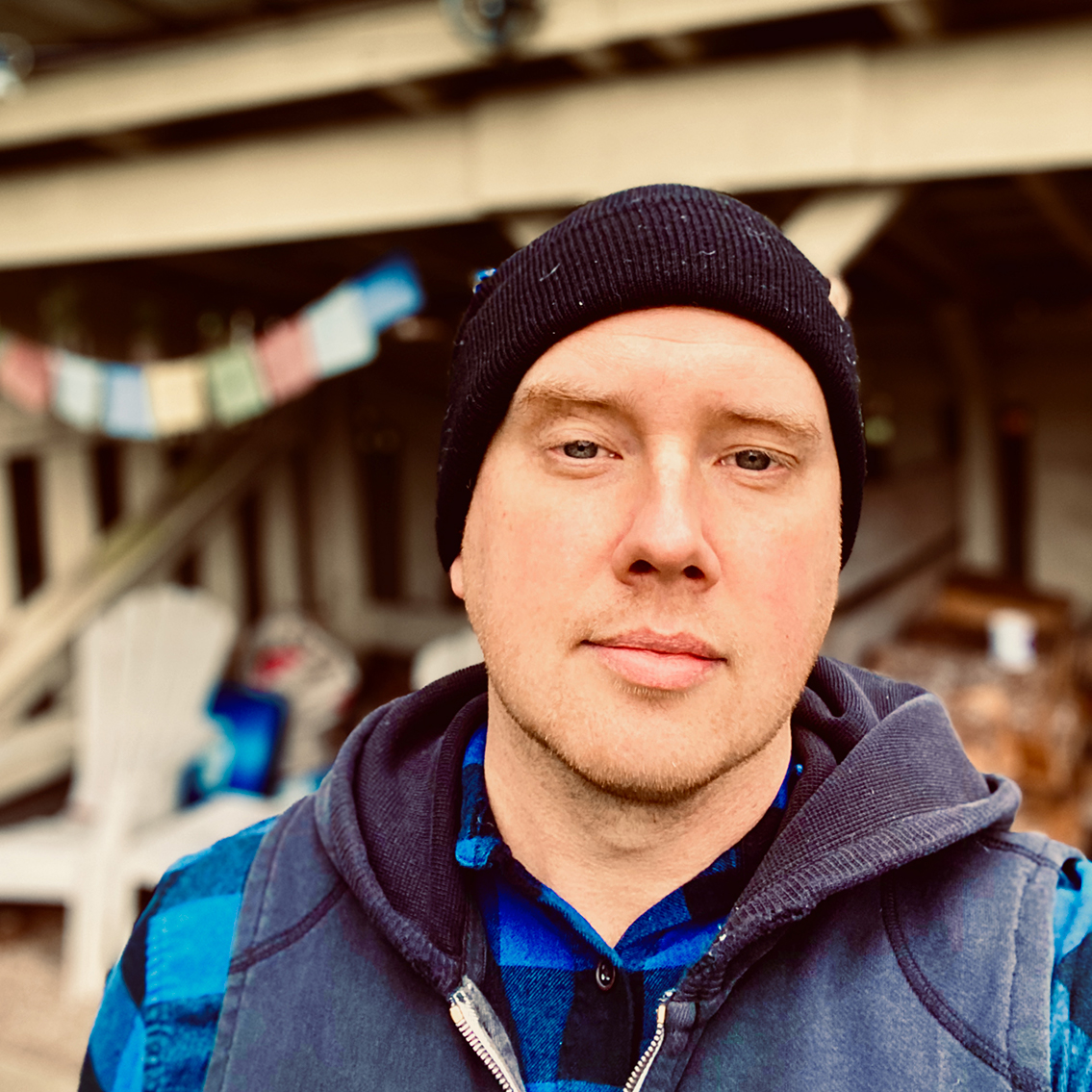 Headshot of Benjamin Borowski in a blue flannel, black hoodie, and black wool hat